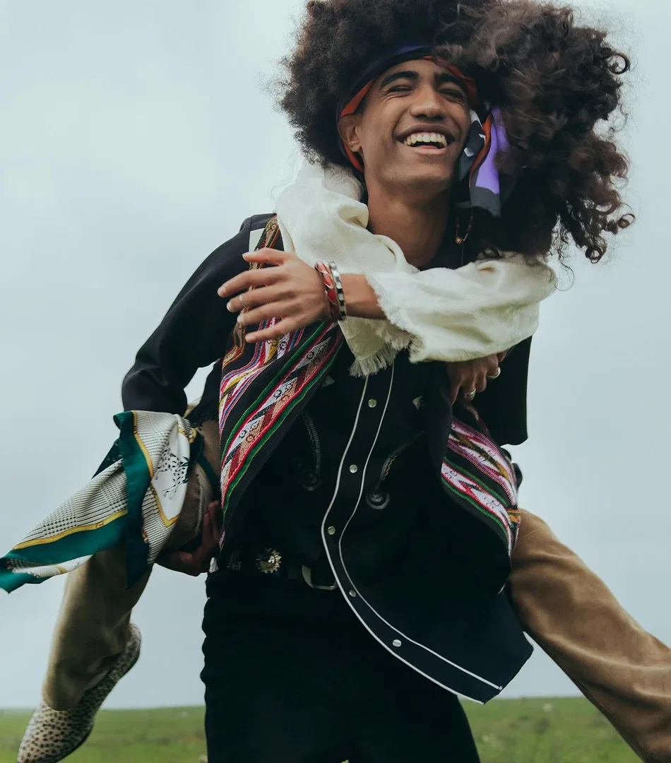 Two people laughing outdoors, one carrying the other on their back